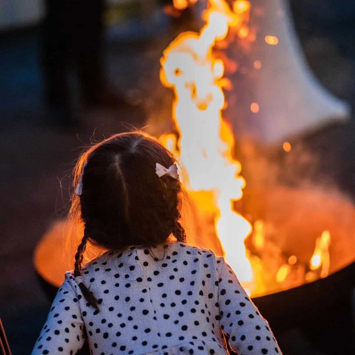 Mädchen steht vor einer lodernden Feuerschale